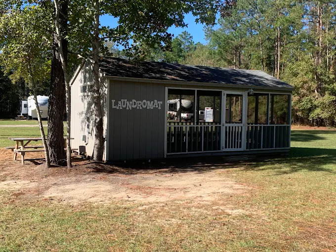 The on-site laundromat, a screened building with LAUNDROMAT painted on the side, under shade trees